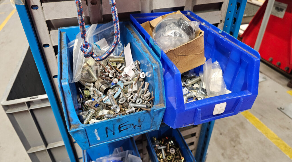 Deux bacs contenant divers vis et boulons stockés sur une étagère en métal.
