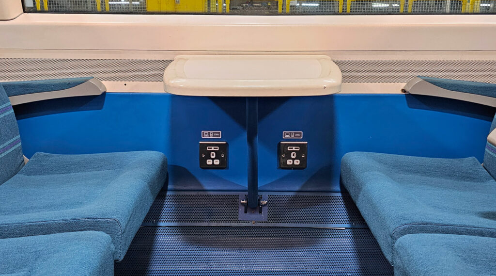 Intérieur d'un compartiment de train avec des prises de chargement sur le mur.
