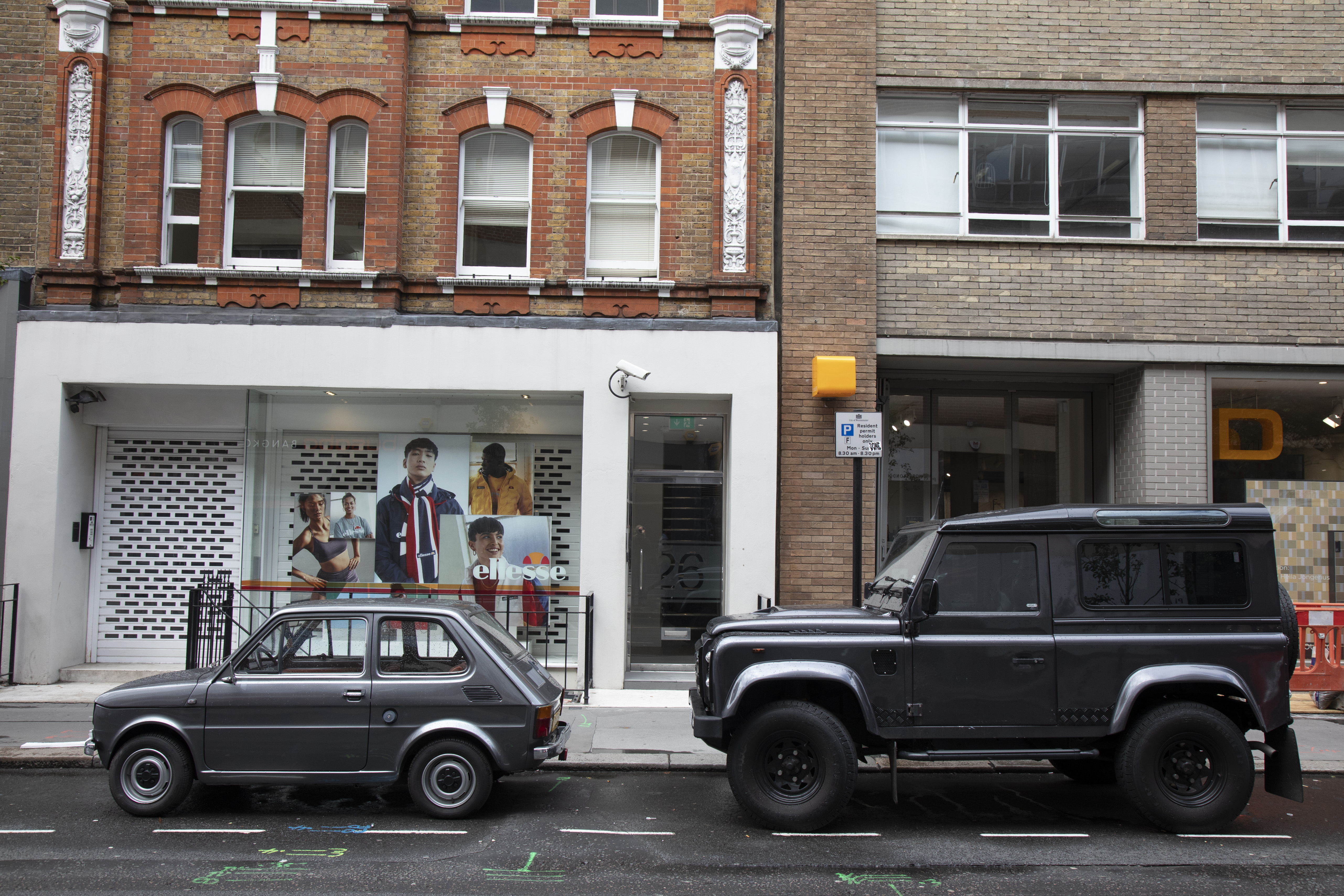 Une petite voiture Fiat 126 et un large Land Rover Defender dans les rues de Londres.