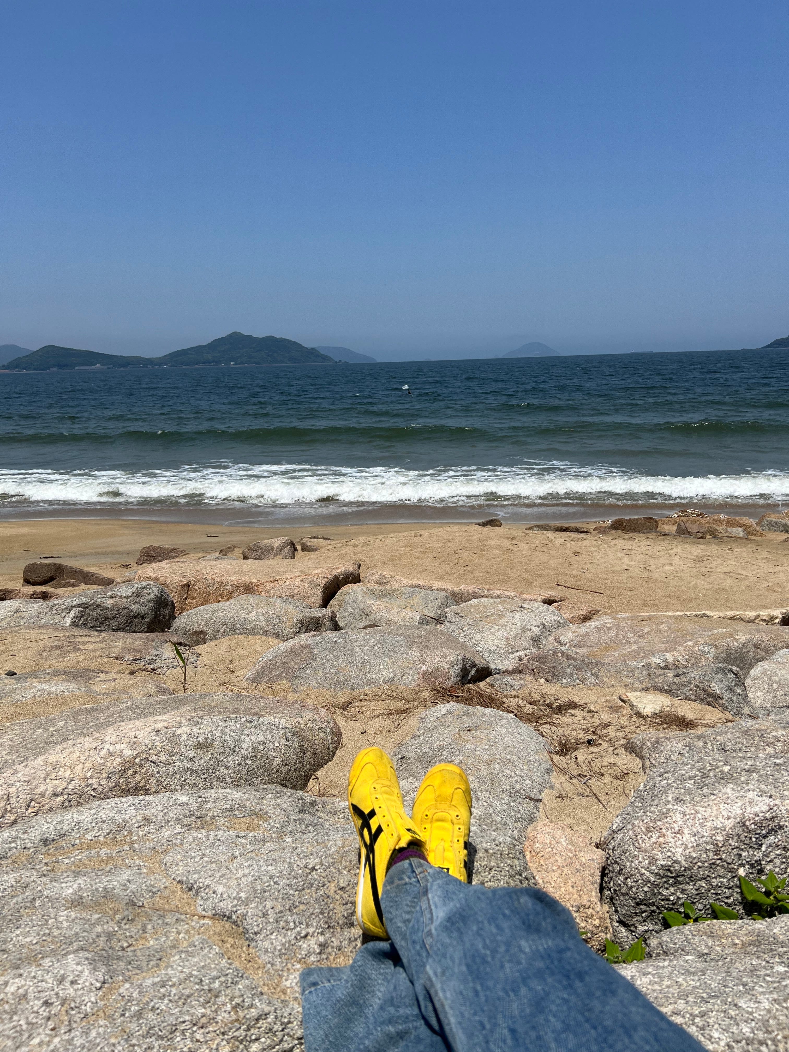 Des baskets jaunes sur un rocher près de la mer au Japon.
